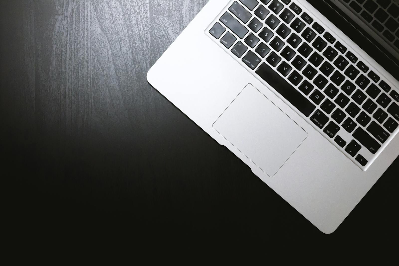 Top view of a sleek laptop on a dark wooden desk, showcasing modern technology.