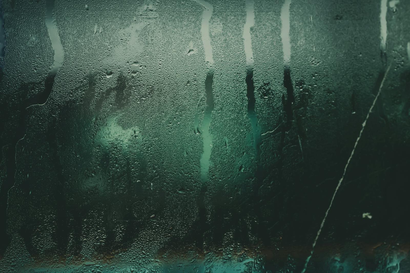 Close-up of a moist glass surface with water droplets and streaks creating an abstract texture.